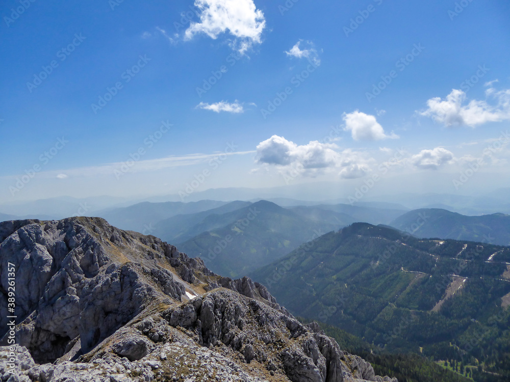 A panoramic view on a massive, stony mountains in Hochturm region, Austrian Alps. There are endless mountains chains in the back. The slopes are overgrown with moss and grass. Sunny and bright day.