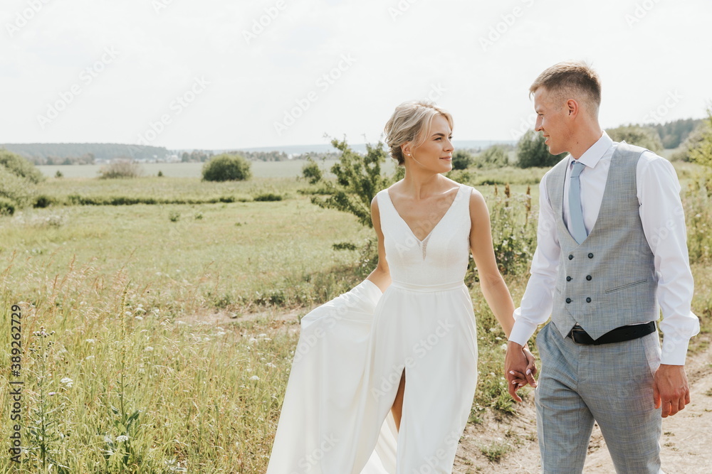 Beautiful happy couple, man and woman are walking in nature together. A young woman in a white dress and a man in trousers and a shirt. Love and Valentine's Day concept. Beautiful happy couple, man and woman are walking in nature together. A young woman in a white dress and a man in trousers and a shirt. Love and Valentine's Day concept.