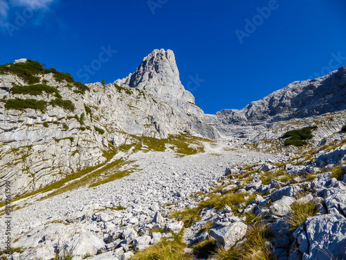 A close up view on a massive, stony mountains in Hochtor region, Austrian Alps. The steep slopes are barely overgrown with grass. Sharp peaks. Dangerous mountaineering. Sunny summer day. Adventure