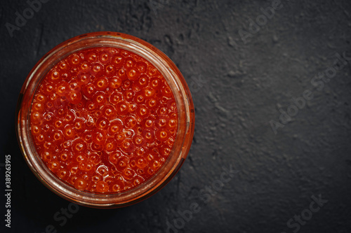 Red caviar in a glass bowl on a dark background. Top view, seafood, chum salmon caviar.