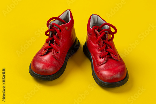 Children's leather shoes in red on a yellow background. Care for health.