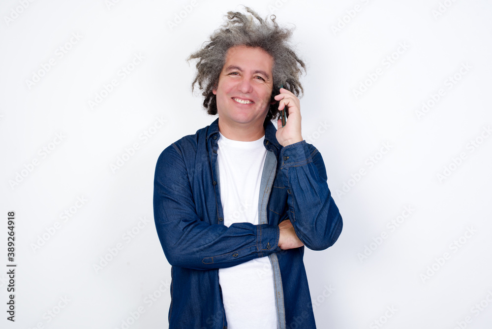 Portrait of a smiling handsome mature caucasian man with afro gray hair standing over white background. Business, confidence and communication concept. Portrait of a smiling handsome mature caucasian man with afro gray hair standing over white background. Business, confidence and communication concept.