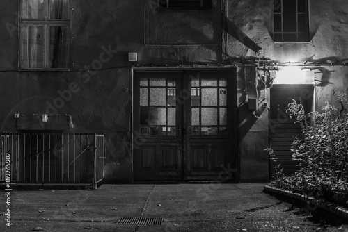 Weathered facade of a house at night, gate of a house passage, unrenovated house in Berlin, at night, black and white photo photo