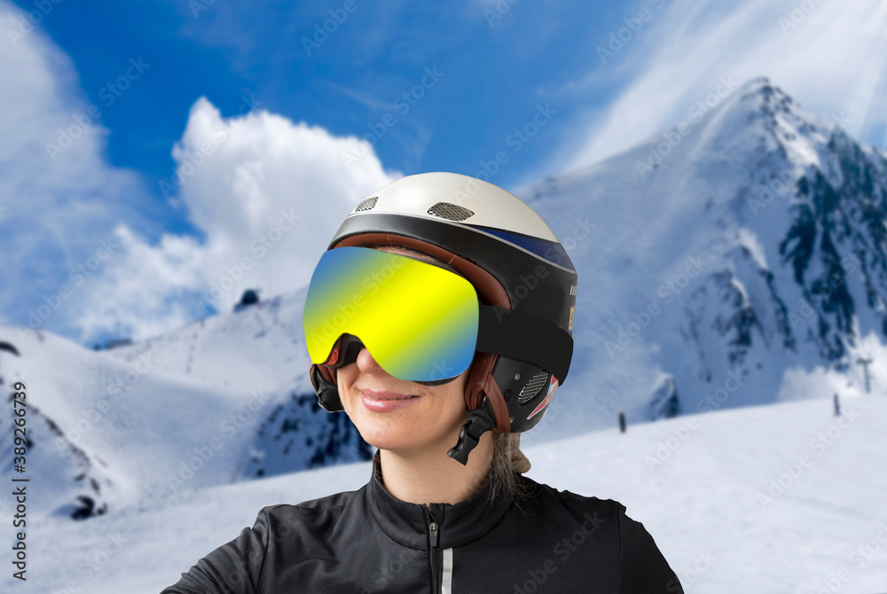 Portrait of a woman in a ski helmet and protective reflective goggles against the backdrop of beautiful winter mountains. Sports, recreation and winter sports