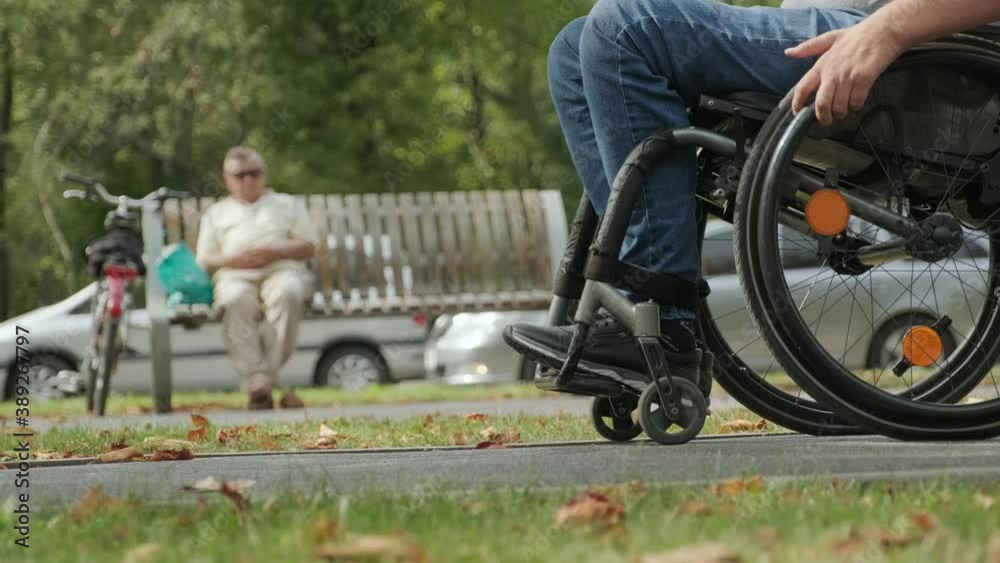 Handicapped man in wheelchair walk at the park alley Handicapped man in wheelchair walk at the park alley