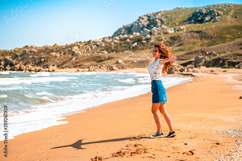 Beautiful young woman with long hair walks along the Black sea on the beach © KseniaJoyg