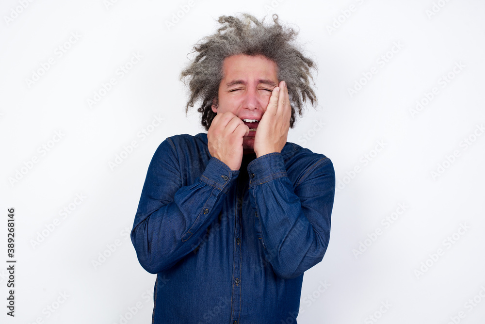 Doleful desperate Handsome mature caucasian man with afro grey hair crying being in depression after quarrel with wife or girlfriend, looks stressfully, frowns face, .feels lonely and anxious Doleful desperate Handsome mature caucasian man with afro grey hair crying being in depression after quarrel with wife or girlfriend, looks stressfully, frowns face, .feels lonely and anxious