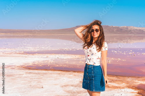 Portrait of a young woman on the background of a pink salt lake in Crimea on a Sunny day