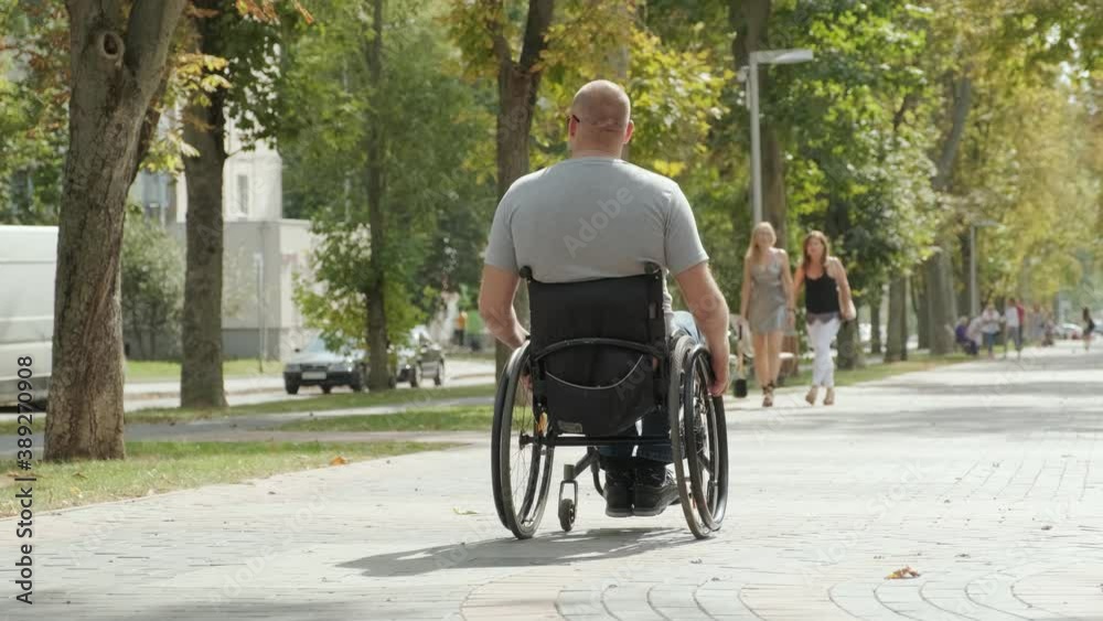Handicapped man in wheelchair walk at the park alley Handicapped man in wheelchair walk at the park alley