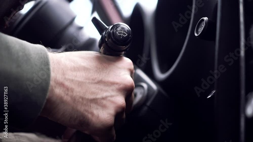 Male hand puts car key into socket and starts engine, colorful lights on control panel, close up. Footage. Starting old classic car motor.