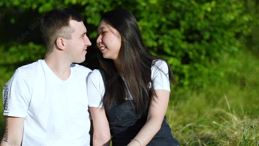 A young international interracial couple in love communicates on a vacation in nature on a clear Sunny evening. Romantic date. A young international interracial couple in love communicates on a vacation in nature on a clear Sunny evening. Romantic date.