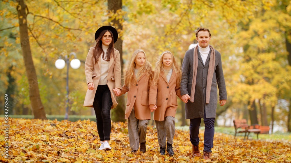 Closeup Happy Family On Autumn Walk. Mother Father and Children Twins Walking Holding Hands In The Park And Enjoying The Beautiful Autumn Nature. Friendly Family Kid Concept Autumn Countryside Closeup Happy Family On Autumn Walk. Mother Father and Children Twins Walking Holding Hands In The Park And Enjoying The Beautiful Autumn Nature. Friendly Family Kid Concept Autumn Countryside