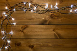 Christmas lights garland on natural wood boards background with copy space.