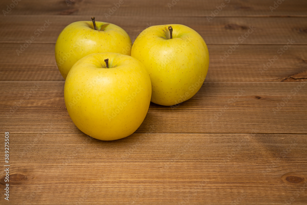 Three beautiful yellow ripe Golden apples on wooden table. Sweet and juicy fruits. Three beautiful yellow ripe Golden apples on wooden table. Sweet and juicy fruits.