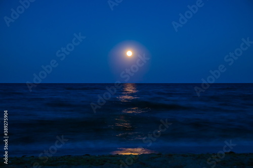 Fototapeta Naklejka Na Ścianę i Meble -  Landscape moon over horizon on sea and moonlight. Panorama with the luna of night. Lunar path on the water. Long exposure