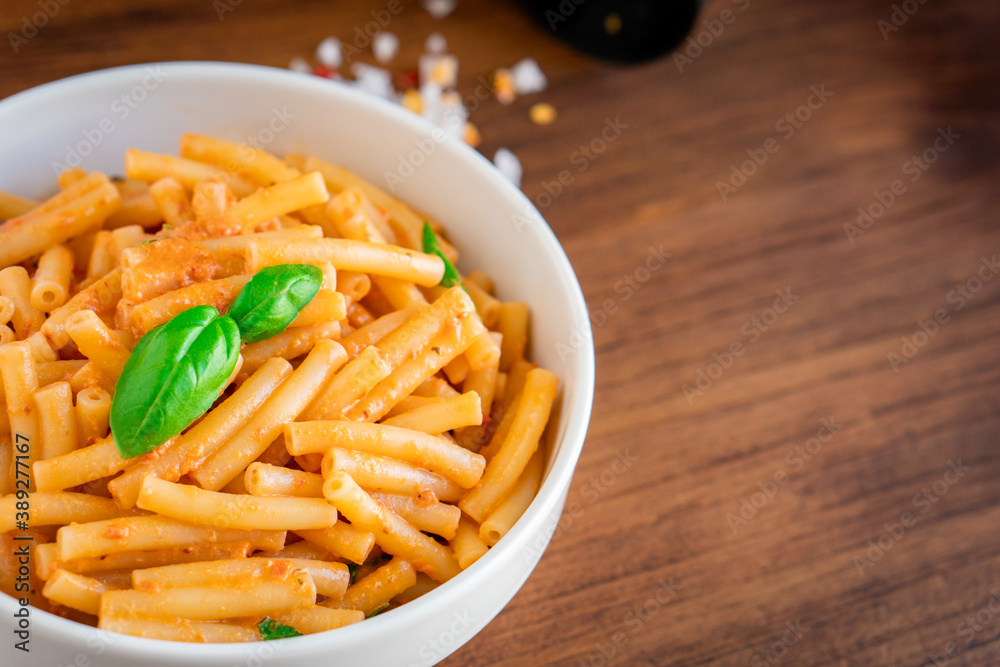 Healthy organic Italian macaroni homemade fresh pasta spaghetti noodles cook with basil tomato garlic pepper sauce with vegan vegetarian recipe in white bowl on wooden vintage table