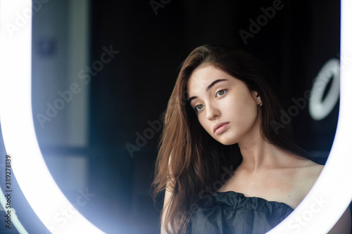 Glamor portrait of beautiful girl model with makeup. The girl is doing makeup and looking in the mirror. Fashion beauty face portrait of beautiful girl. Professional makeup. Fashion style woman.