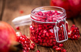 Old wooden table with fresh preserved Pomegranate seeds (close-up shot; selective focus)