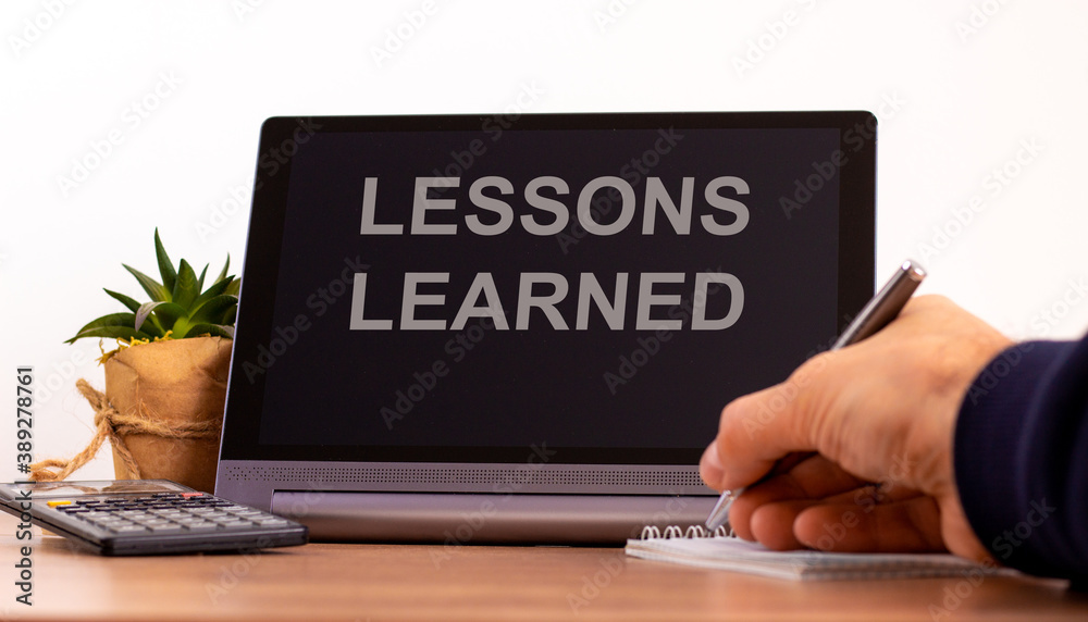 Education concept. Tablet with text 'lessons learned'. Online education during COVID-19 quarantine. Male hand with pen, calculator, copy space.