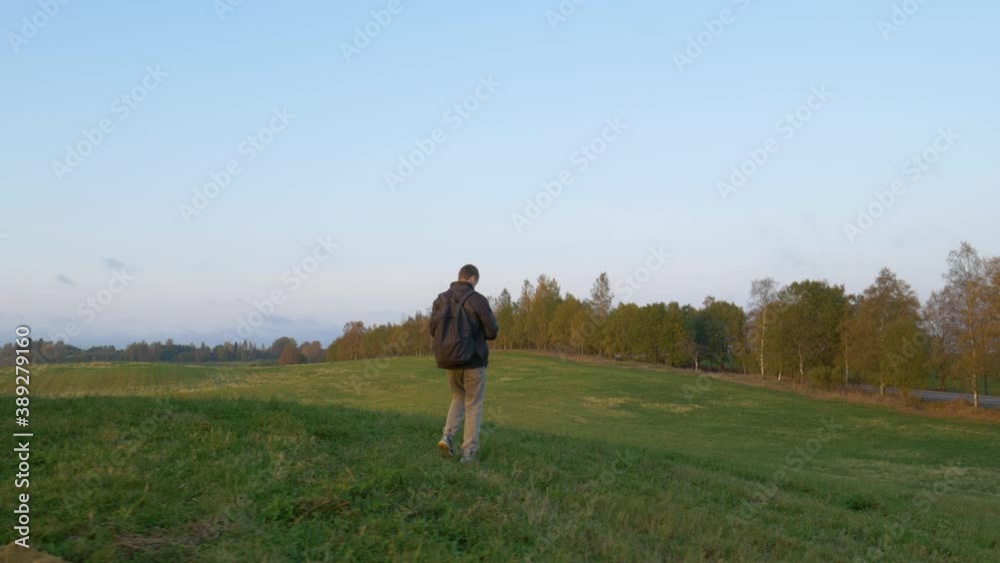 A man descends from a hill and takes pictures of nature. The photographer walks on the grass and takes pictures of the hills. A man descends from a hill and takes pictures of nature. The photographer walks on the grass and takes pictures of the hills.