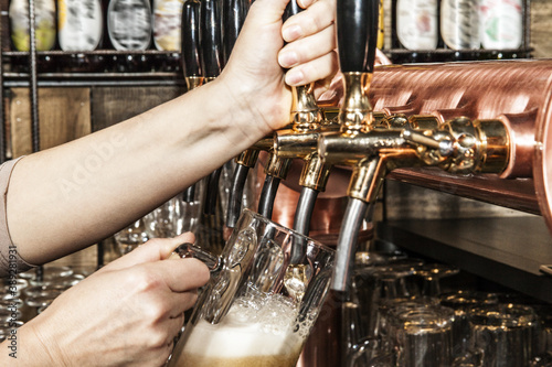 Pouring a beer into a mug from tap. Inside a pub.