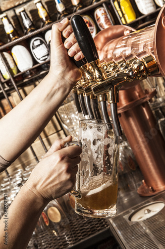 Pouring a beer into a mug from tap. Inside a pub.
