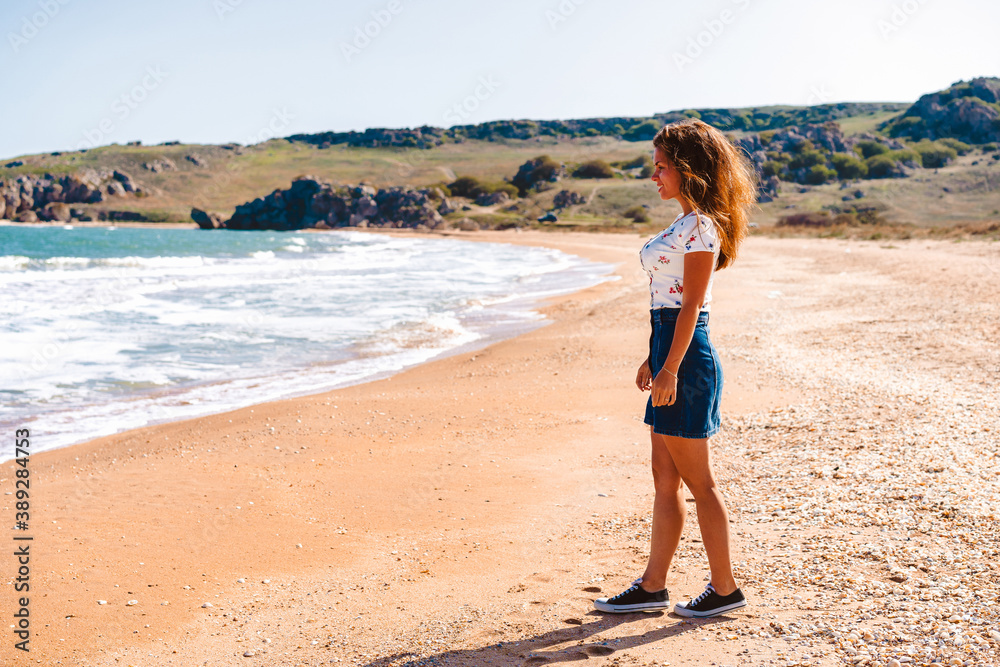 Beautiful young woman with long hair walks along the Black sea on the beach