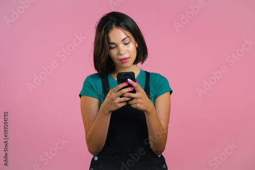 Attractive brunette woman receives happy notification on mobile phone. Girl using smartphone. Technology concept.