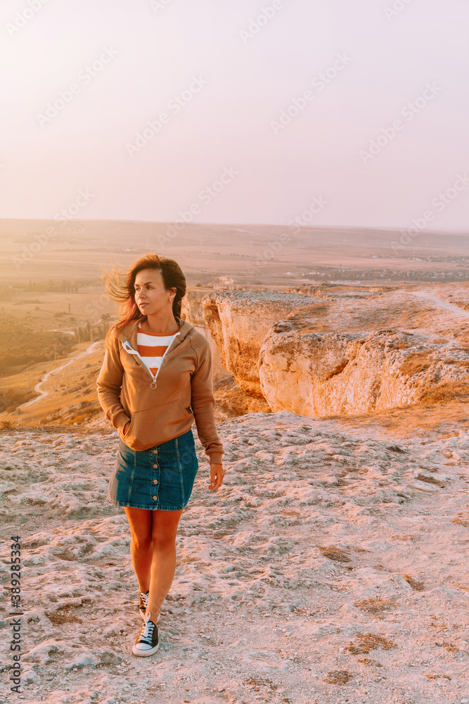 Portrait of a young woman on a mountain in an orange sunset Portrait of a young woman on a mountain in an orange sunset