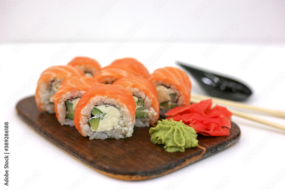 Philadelphia rolls with salmon on white table next to chopsticks, wasabi and ginger. Sushi menu. Japanese food concept. Place for text Philadelphia rolls with salmon on white table next to chopsticks, wasabi and ginger. Sushi menu. Japanese food concept. Place for text