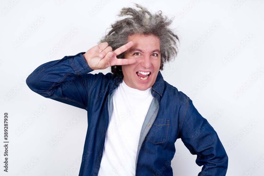 Leisure lifestyle people person celebrate flirt coquettish concept. Handsome young cheerful blond man showing making v-sign near eyes wearing casual clothes standing outdoors. Leisure lifestyle people person celebrate flirt coquettish concept. Handsome young cheerful blond man showing making v-sign near eyes wearing casual clothes standing outdoors.