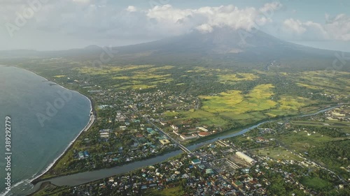 Tropic cityscape at sea bay river banks aerial. Streets with cottages and lodges with traffic road. Green valley at Mayon volcano Legazpi city, Philippines. Nobody nature landscape at mist haze photo