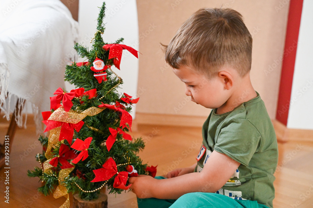 A child near the Christmas tree opens a gift