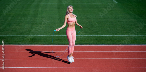 Warming up. jumping on outdoor arena. training and workout. athletic female coach with skipping rope. woman sport trainer. healthy sporty lifestyle. health and energy. sexy lady in fitness sportswear