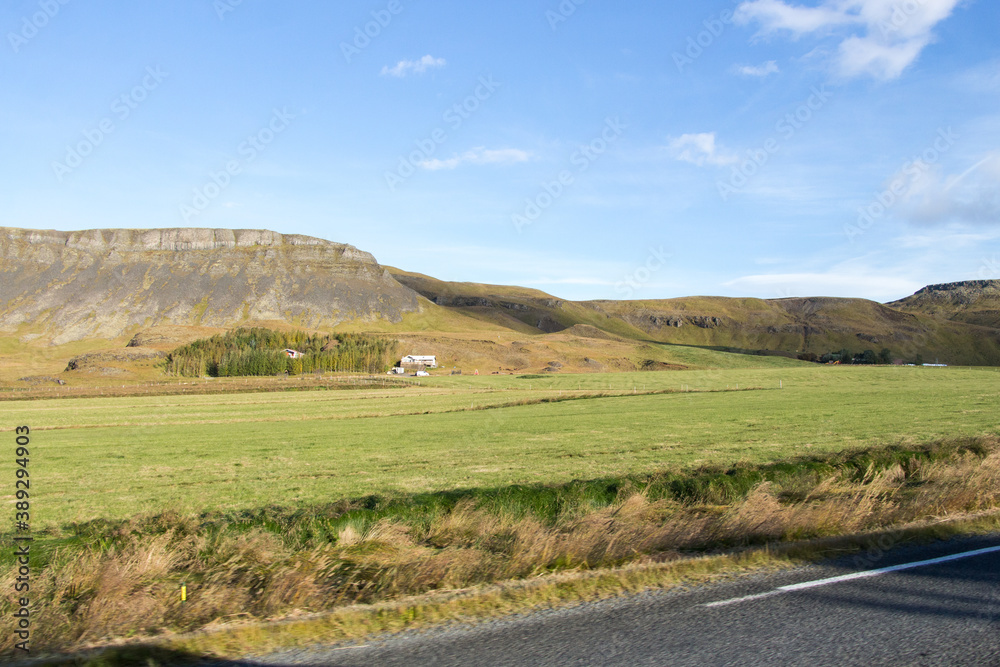 SOUTH ICELAND, SEPTEMBER 19, 2018: Farm fields on the road in southern Iceland with green grass and blue skies during autumn.