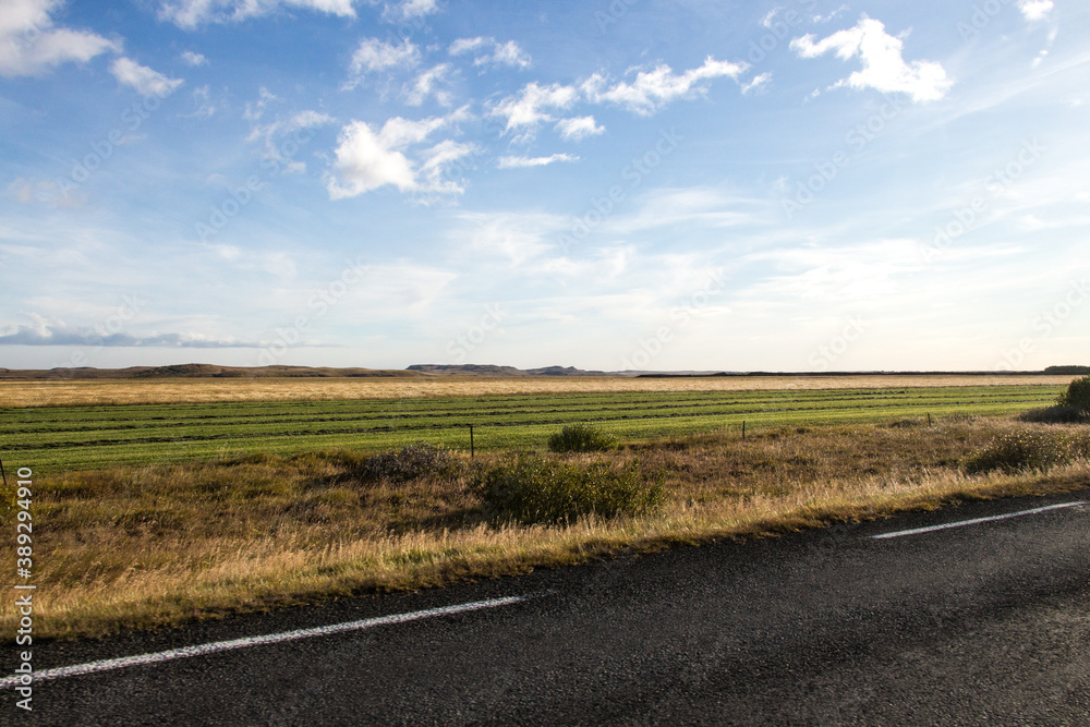 SOUTH ICELAND, SEPTEMBER 19, 2018: Farm fields on the road in southern Iceland with green grass and blue skies during autumn.