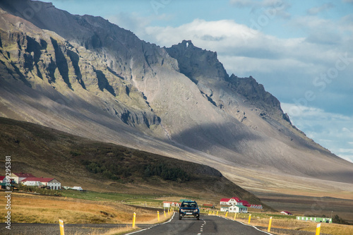 RING ROAD, SOUTH ICELAND - SEPTEMBER 19, 2018: Single 4x4 car driving on Route 1 in Southern Iceland, in a nice autumn day. Mountains in the background and a few farm houses along the road.