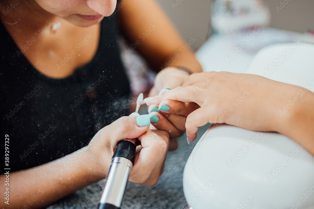 Obraz premium Young woman getting a beautiful manicure in the salon. The process of making nails.