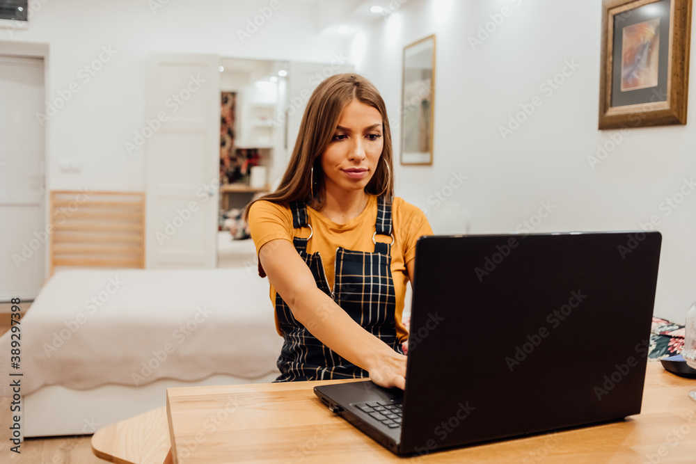 Beautiful young businesswoman working on a laptop while talking to a mobile phone. Beautiful young businesswoman working on a laptop while talking to a mobile phone.