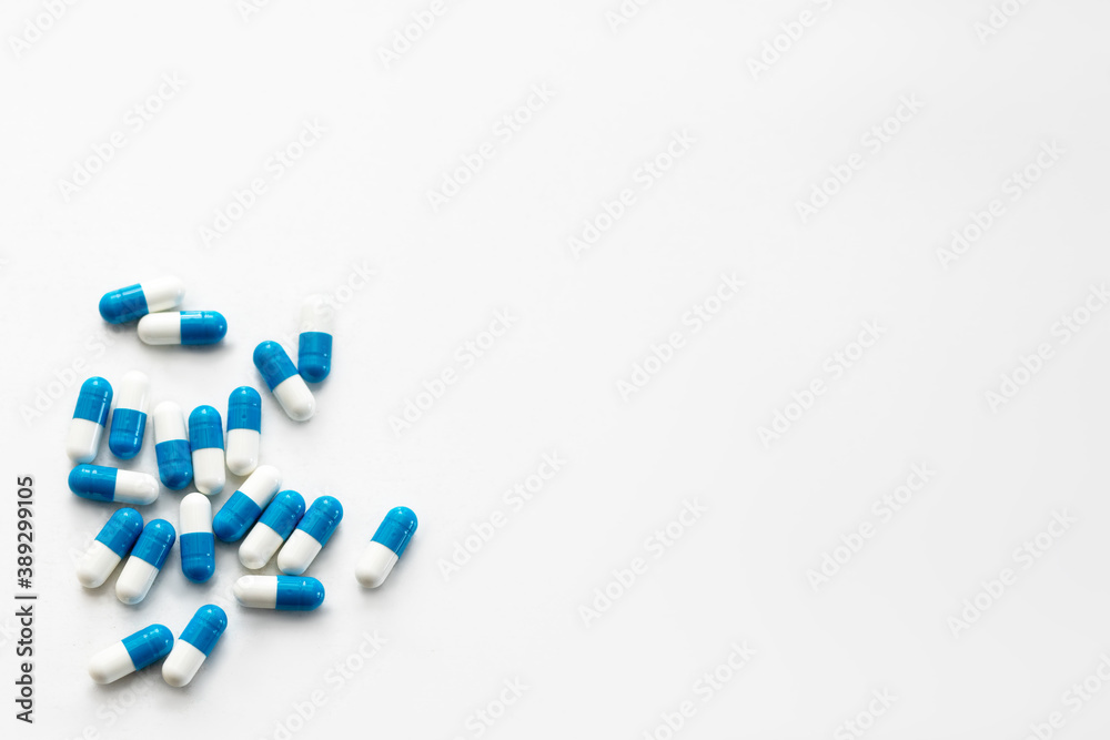 Scattered white and blue pills on white table. Mock up for special offers, advertising, web background or other ideas. Medical, pharmacy, healthcare concept. Copy space. Empty place for text or logo. Scattered white and blue pills on white table. Mock up for special offers, advertising, web background or other ideas. Medical, pharmacy, healthcare concept. Copy space. Empty place for text or logo.