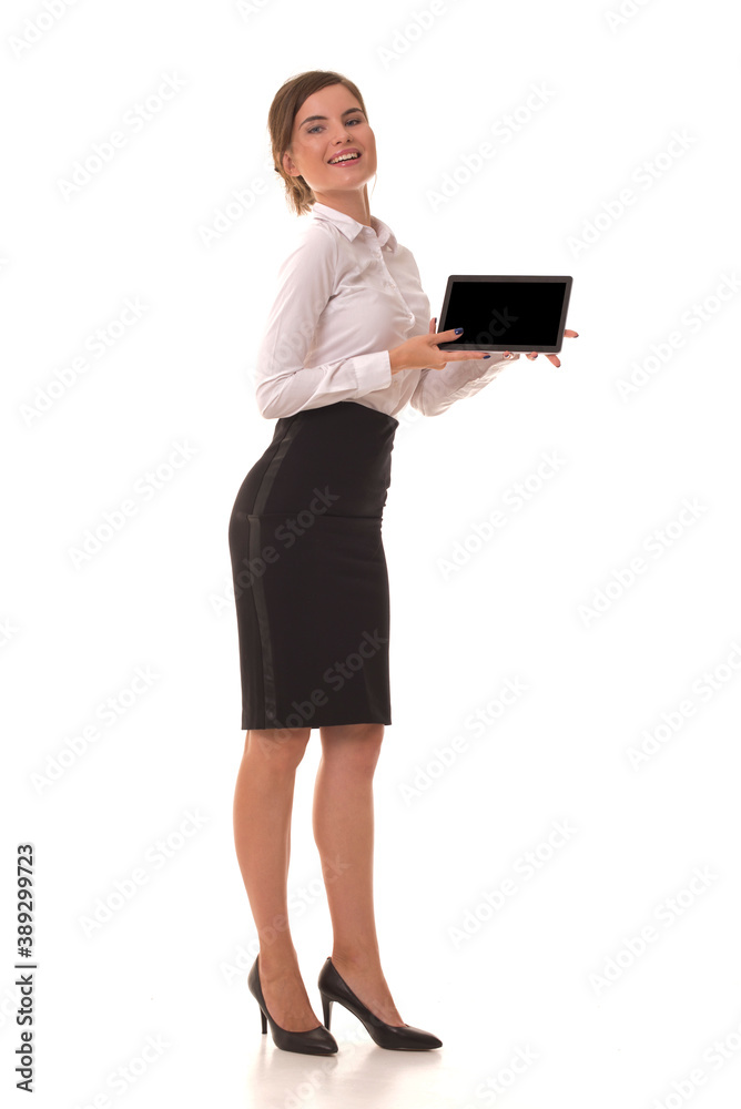 Girl stands on a white background and holds a tablet in her hands. Girl in a skirt and white shirt with a tablet in her hands. Girl stands on a white background and holds a tablet in her hands. Girl in a skirt and white shirt with a tablet in her hands.