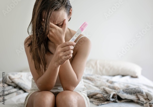 Fényképezés Depressed stressed woman trying to conceive, holding a negative pregnancy test result
