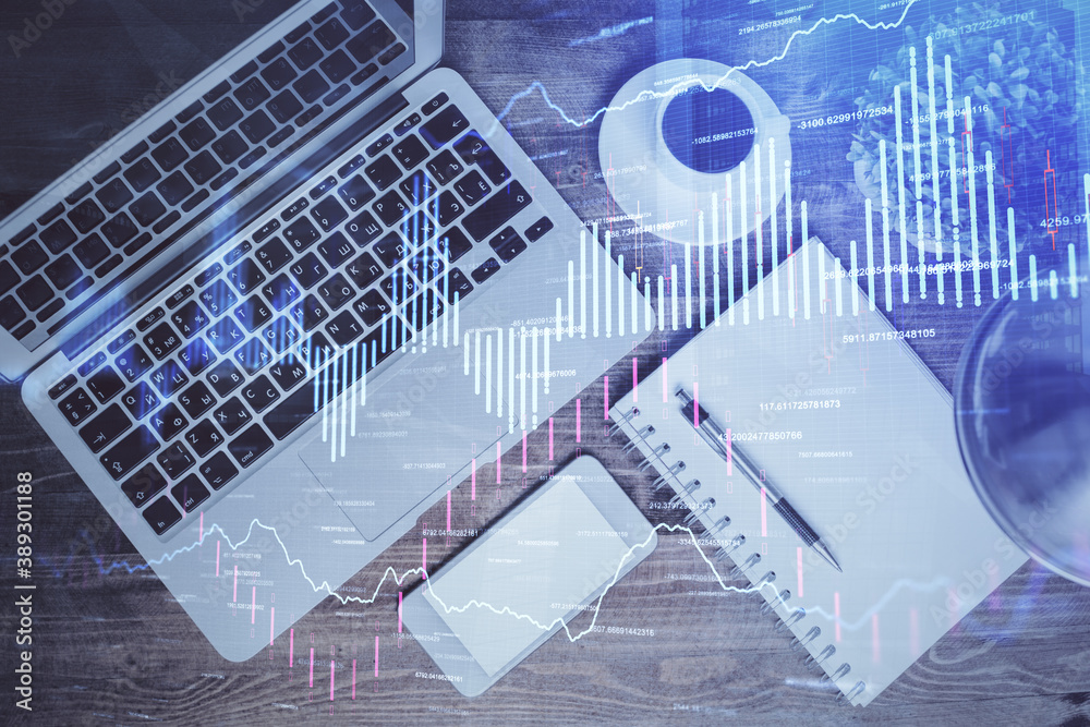 Financial market graph and top view computer on the desktop background. Double exposure. Investment concept. Financial market graph and top view computer on the desktop background. Double exposure. Investment concept.