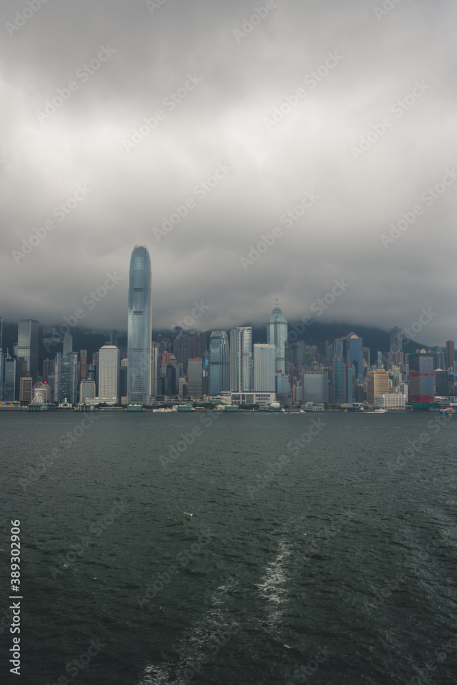 Obraz premium urban city skyline during clear summer day with densely packed buildings in victoria harbour in hong kong