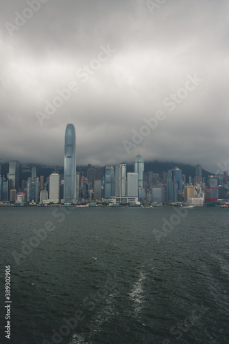 urban city skyline during clear summer day with densely packed buildings in victoria harbour in hong kong