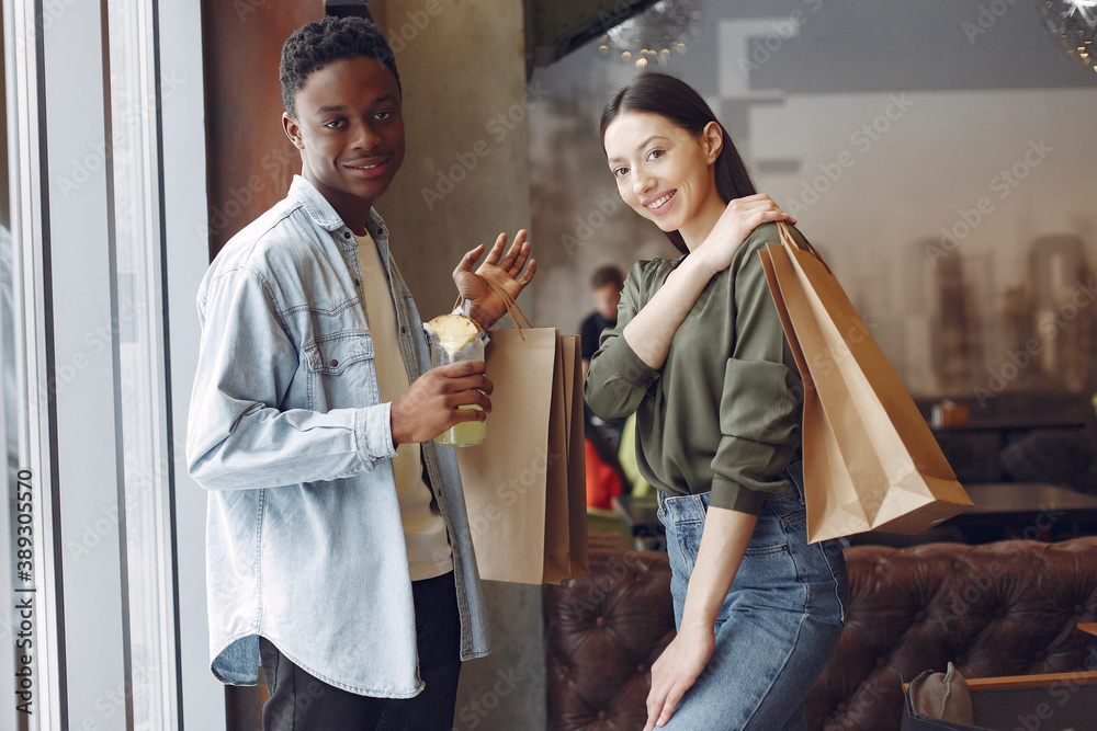 Black man in a cafe. International people. Man in a blue shirt. Woman in a green blouse. People with shopping bags.