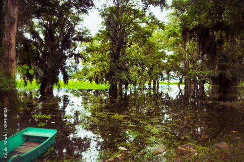 A canoe and many trees and their reflection in the water at Lago de Yojoa in Honduras photo