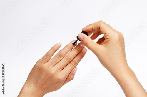 manicure applying  brushing fingernails with clear enamel  nail painting transparent nail polish on white background