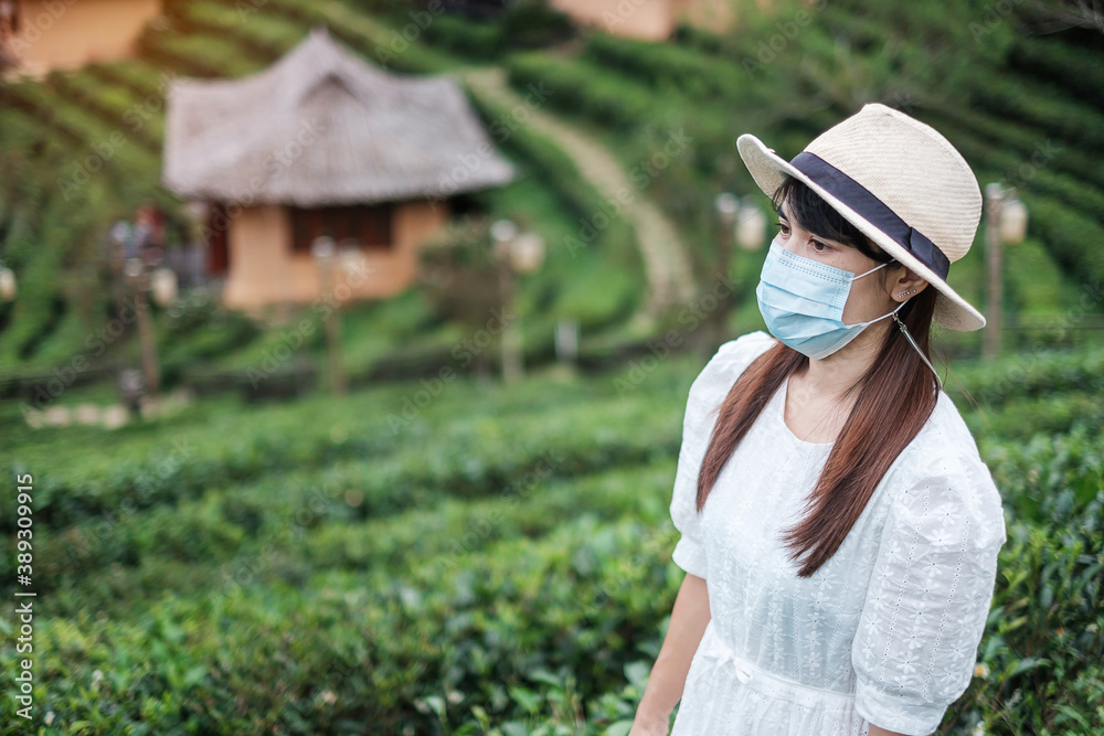 Obraz premium Happy tourist woman wearing surgical face mask enjoy beautiful Tea garden, protection Coronavirus disease (Covid-19) infection. New Normal, travel, vacation and holiday concept