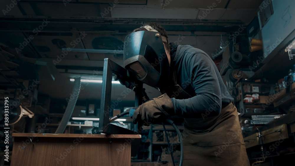 Worker wearing a mask and gloves soldering metal parts Worker wearing a mask and gloves soldering metal parts